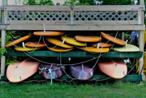 Colorful kayaks and paddleboards neatly stacked outdoors, perfect for water sports enthusiasts.